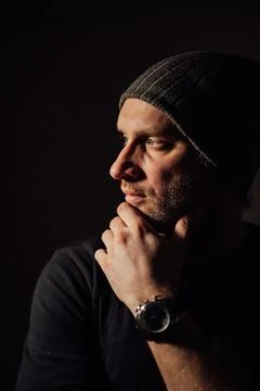 Serious dramatic man looking away while standing against black studio background Stock Photos