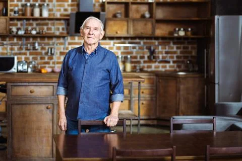 Serious elderly man standing in the kitchen Stock Photos