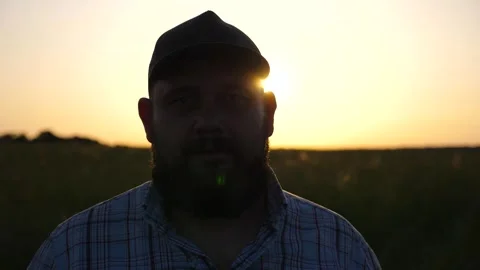 Serious farmer in cap looks into camera standing at cultivated field. Portrait Видео 337054309