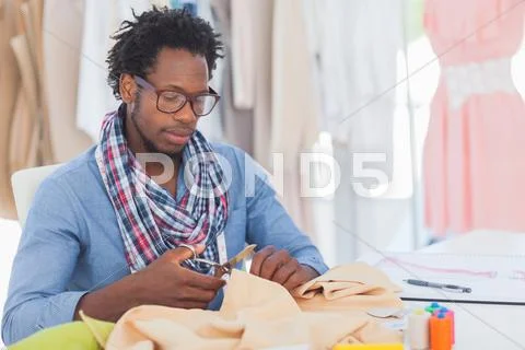 Serious fashion designer cutting textile Stock-Fotos