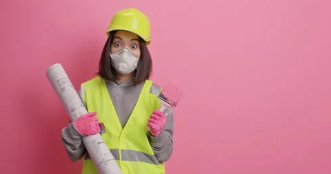 Serious female architect considers future design of room looks attentively hods Stock Footage 157334905