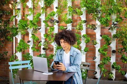 Serious, focused ethnic men using laptop, smartphone at outdoor internet cafe Stock Photos