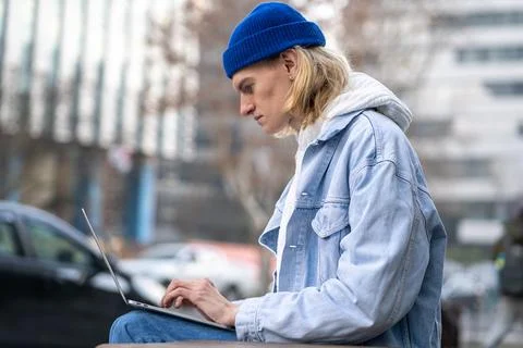 Serious focused freelancer IT guy engrossed in laptop remote work on urban 写真素材