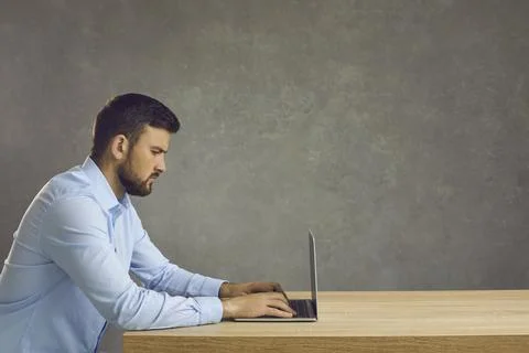 Serious focused smart programmer or employee working with laptop on deadline Stockfoto's