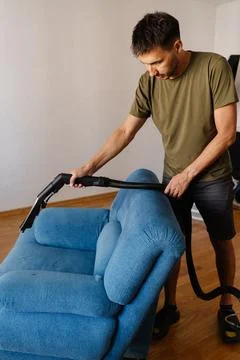 Serious focused young man using washing vacuum cleaner to remove dirt and stains Stock Photos