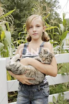 Serious girl holding cat in garden Stock-Fotos