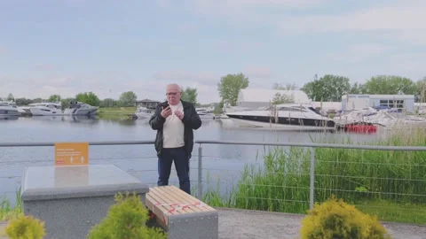 Serious grey haired pensioner talks on phone against yachts Video stock 135443228