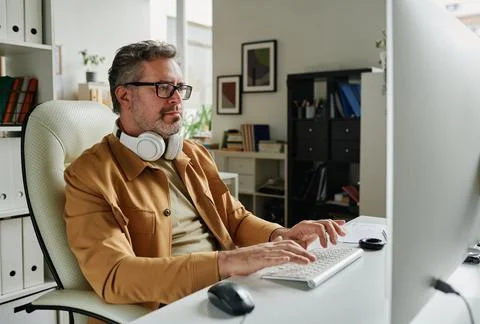 Serious grey haired programmer looking at computer screen 스톡 사진