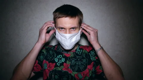 Serious guy puts on a protective mask and looks into the frame. Stock Footage 128979587