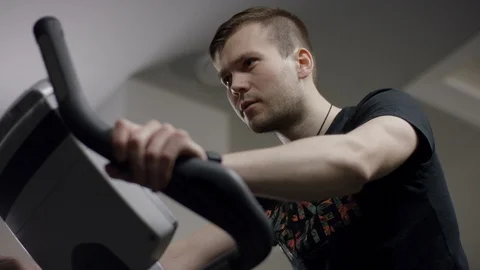 Serious guy start pedals on the new exercise bike and track the time in the new Stock Footage 91621132