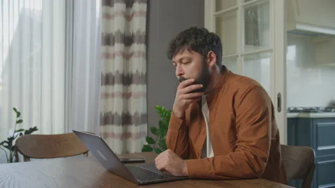 Serious guy thinks behind a laptop computer Stockbeeldmateriaal 195856291