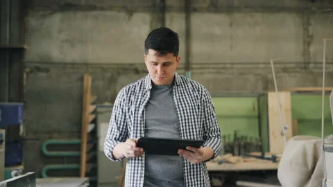 Serious guy working with tablet in wood workshop walking in room looking around Video stock 113741023