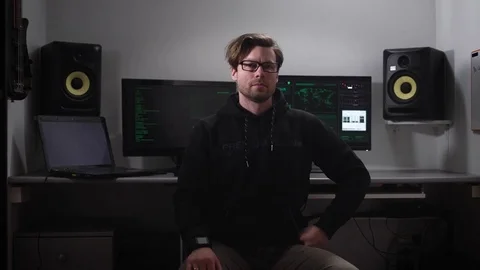 Serious hacker looking directly the shot, he is dressed in a dark jacket Stock Footage 72415199
