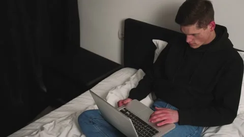Serious handsome caucasian man using laptop on bed late at night before falling Stock Footage 148385789