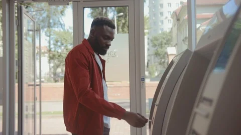 Serious handsome young man inserting credit card into bancomat entering a pin to Stock Footage 110482860