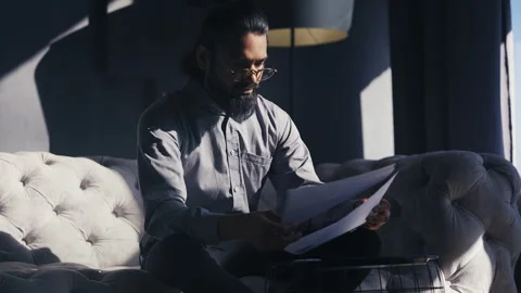 Serious Indian accountant reading documents, analyzing company profit report Stock Footage 316837393