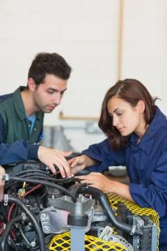 Serious instructor and trainee checking a machine Stock Photos