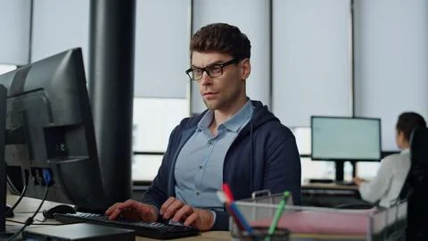 Serious it guy typing computer in office. Professional programmer code using two Stock Photos