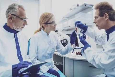 Serious lab assistant demonstrating test tube Stock Photos
