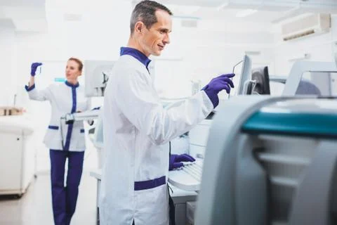 Serious lab assistant looking at screen of computer Foto stock