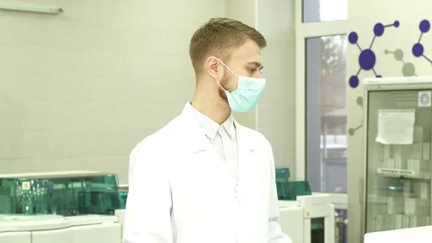 A serious lab assistant stands in the middle of the laboratory and turns his Stock Footage 84864340