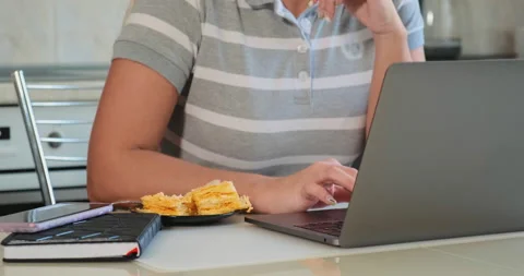 Serious lady eats cake and types Stock Footage 131073362