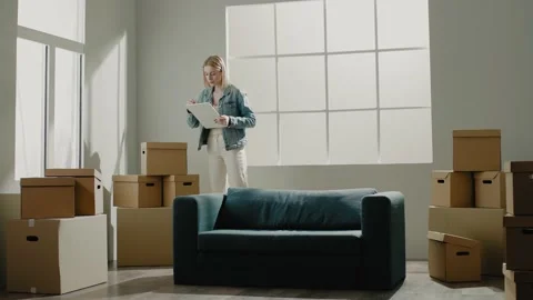 Serious lady examines cardboard boxes after relocation Stock Footage 150831519