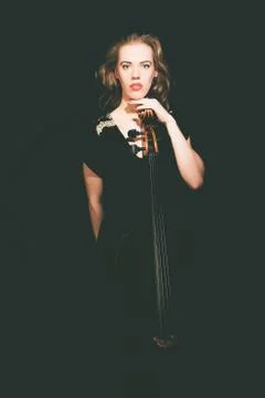 Serious Lady Leaning on a Cello, Staring at Camera Stock Photos