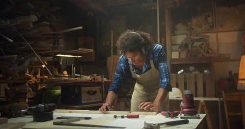 Serious Latin curly master carpentry in apron marking with pencil measurements Stock Footage 140553355