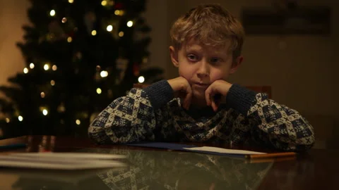 Serious little boy sitting thinking about presents writing letter to Santa Claus Stock-Footage 160465219