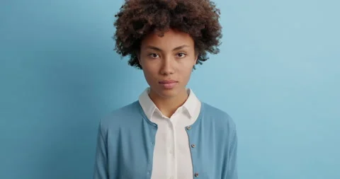 Serious looking dark skinned Afro American woman with natural curly hair focused Stock Footage 143625613