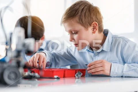 Serious male child sitting near constructor at table Stock Photos