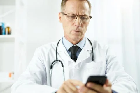 Serious male doctor using mobile phone at work Stock Photos
