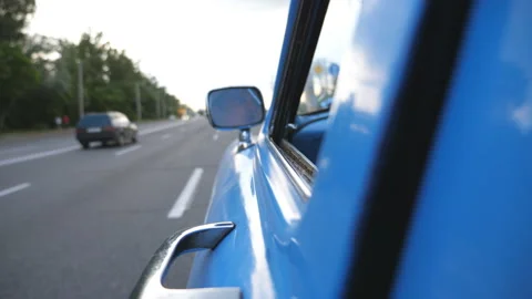 Serious male driver is reflected in left side mirror of the moving retro car Stock Footage 229343568