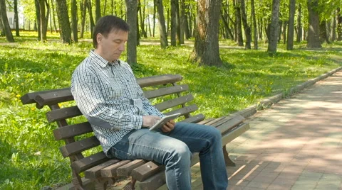 Serious male working on tablet computer in the park Stock Footage 63160477
