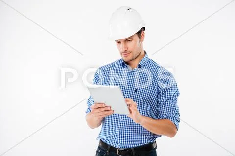 Serious man architect in hard hat standing and using tablet Stock Photos