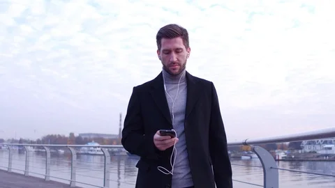 Serious man checking time at hand watches, walking on city embankment with Stock Footage 101125746
