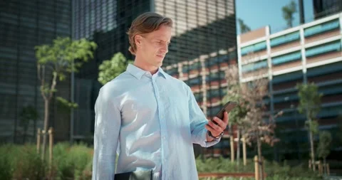 Serious man checking time on mobile phone and hand watches urban business center Stock Footage 136675197