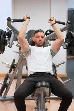 Serious man doing shoulder press workout in gym. Foto stock