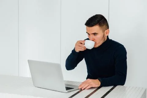 Serious man drinking tea while working with a laptop at home Stock Photos