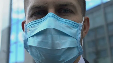 Serious man in facemask looking at camera, concerned about air pollution in city Video stock 117223259