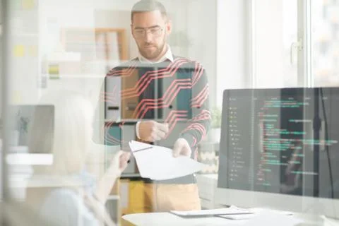 Serious man giving papers with code to lady programmer Stock Photos
