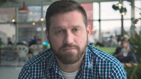 Serious man looking to camera, portrait, in cafe, very close steadicam shot 库存影片 72953821