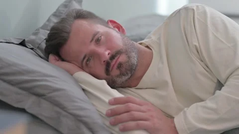 Serious Man Looking at Camera while Lying on Side in Bed Video stock 287899303