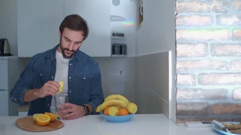 Serious man preparing fresh fruit juice in the kitchen Stock Footage 127648957