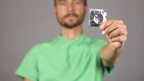 Serious man raises in front on left outstretched hand condom Video stock 94926789