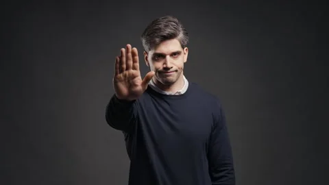 Serious man raises an open palm toward the camera in firm stop gesture. Male exp Stock Footage 346493895
