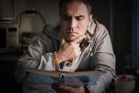 Serious man reading a book with deep concentration at home, studying carefull Stock Photos