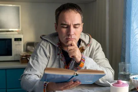 Serious man reading a book with deep concentration at home, studying carefu.. Stock Photos