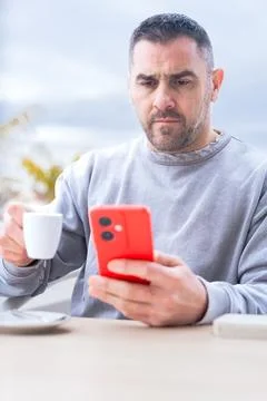 Serious man serious while typing on her smartphone at an outdoor cafe. Stock Photos